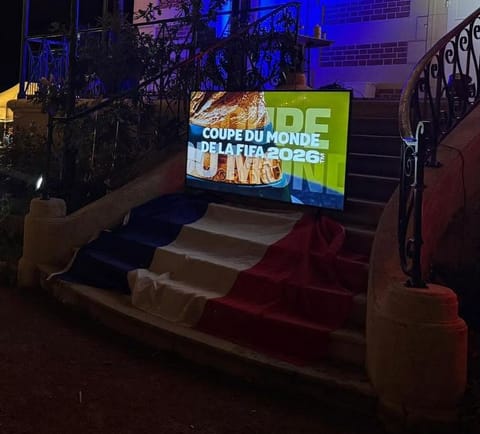 Soirée en plein air sous les guirlandes : l'écran de la Coupe du monde posé sur l'escalier drapé de bleu, blanc, rouge